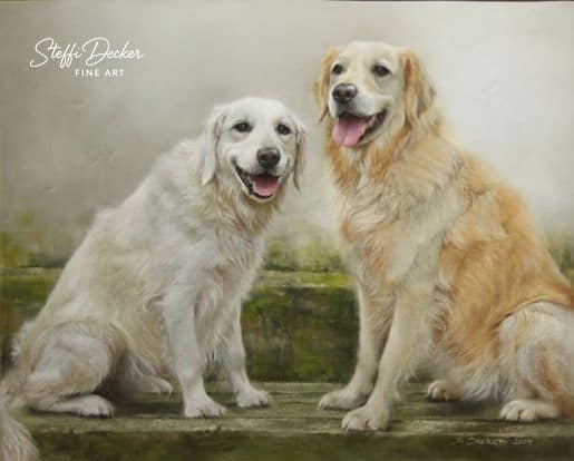 Zwei helle, langhaarige Hunde sitzen nebeneinander auf einem Steinuntergrund vor einem weich verschwommenen, naturfarbenen Hintergrund und blicken mit leicht geöffnetem Maul nach vorn.