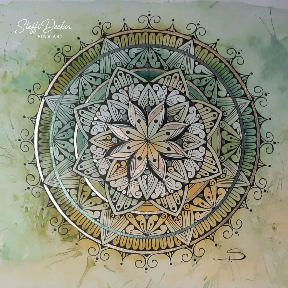 Ein kunstvoll gestaltetes Mandala mit mehreren symmetrischen Ebenen aus blatt‑, fächer‑ und tropfenförmigen Mustern in Grüntönen, Gold und Beige; ein großer sternförmiger Aufbau bildet das Zentrum, während feine Linienornamente und geschwungene Verzierungen den äußeren Kreis umrahmen, auf einem sanft verlaufenden aquarellartigen Hintergrund in Grün und Ocker.